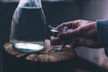 Man drinking strong alcohol drink from a shot glass, close up of hand, selective focus