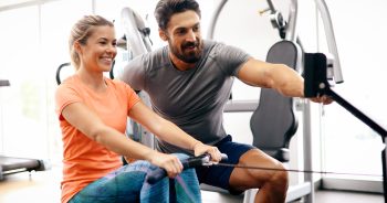 Personal trainer assisting woman lose weight in gym